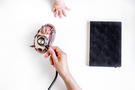 stethoscope, toys and hands on doctors office desk background top viewの写真素材