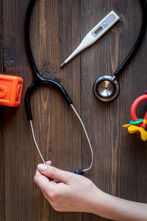 childrens doctor work with stethoscope and toys top view on wooden backgroundの写真素材