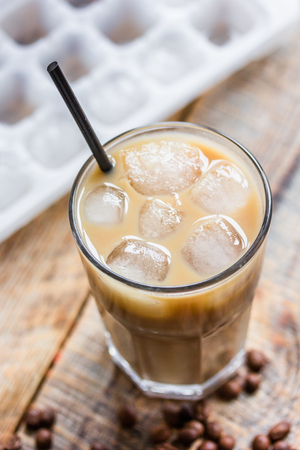 coffee break with cold iced latte and beans on wooden table backgroundの写真素材
