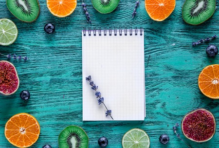 mockup cut citrus, lavender, blueberry, notebook on blue desk background top view
