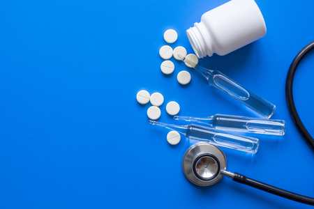 medicine set with stethoscope and vials on doctor's office workplace blue background top view mockupの写真素材