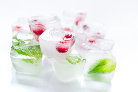 ice cubes with fresh red berries and mint leaves on white table backgroundの写真素材