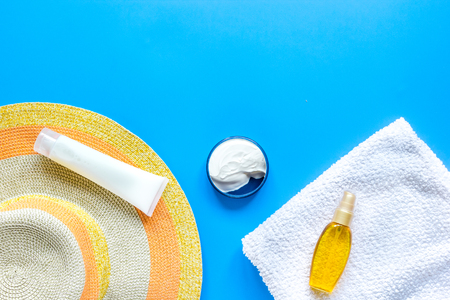 Sun protection composition with hat and body cream on blue desk background top view mockupの写真素材