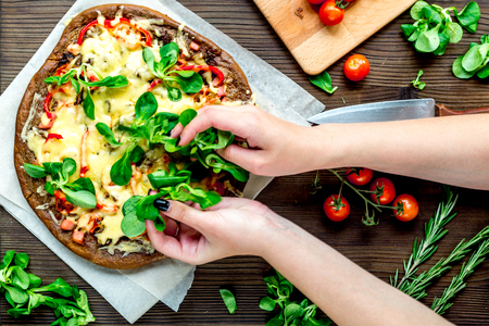 cooking pizza with vegetables and cheese on wooden desk background top viewの写真素材