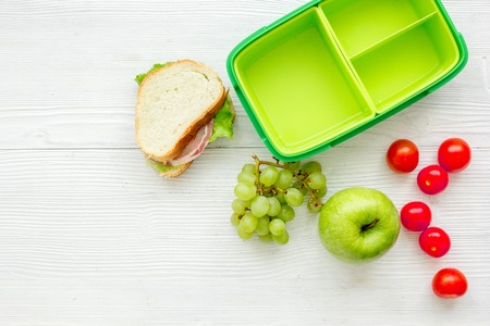 school lunch set with apple and vegetables in lunchbox on white wooden table background top view mock upの写真素材