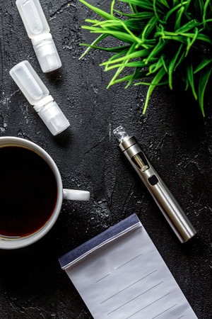 concept of electronic cigarette on dark background top view.