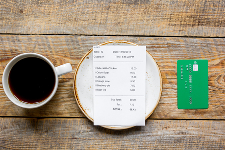 restaurant bill, credit card and coffee on wooden table background top viewの写真素材