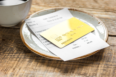 cup of coffee and receipt bill for payment by credit card on wooden table backgroundの写真素材