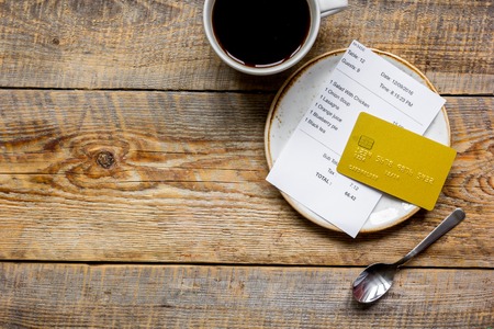 cup of coffee and receipt bill for payment by credit card on wooden table background top view mockupの写真素材