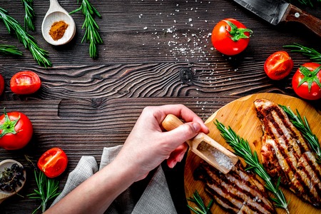 steak cooking with grilled meat, tomato, hands and spices on wooden desk background top view mock-up