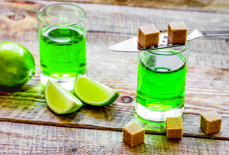 absinthe shots with lime slices and sugar on wooden table backgrの写真素材