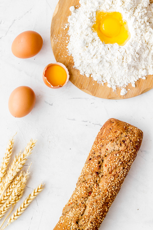 Baking background with eggs, flour and bread on white desk. Top view.