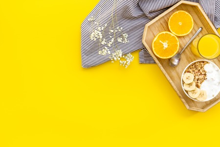 granola with banana slices and orange juice for breakfast on yellow background top view copyspaceの写真素材