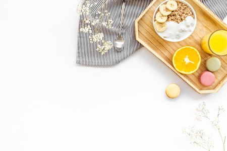 Healthy granola, macaroons and orange juice for colorful breakfast on white background top view...