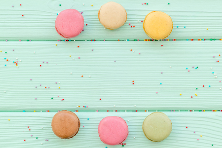sweet dessert pattern with macarons on mint green wooden background flat lay mockupの写真素材