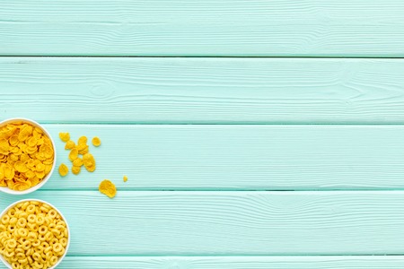 Corn cereals in bowls on mint green wooden background top view space for text