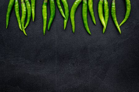 Food ingredients. Fresh green chilli pepper pattern on black table background top view space for textの写真素材