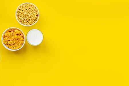 Energy snacks. Various corn cereals in bowls and milk on yellow background top view copyspaceの写真素材