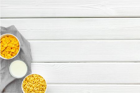 Various corn cereals in bowls and milk on white wooden background top view copyspaceの写真素材