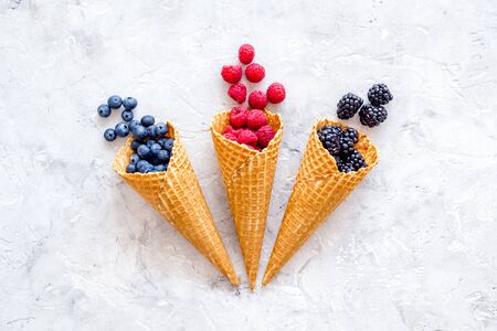 Summer breakfast with fresh berries in waffle cones on light stone background top viewの写真素材