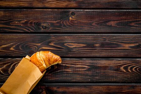 Fresh pastry. Breakfast with croissant in paper bag on wooden background top view mock upの写真素材
