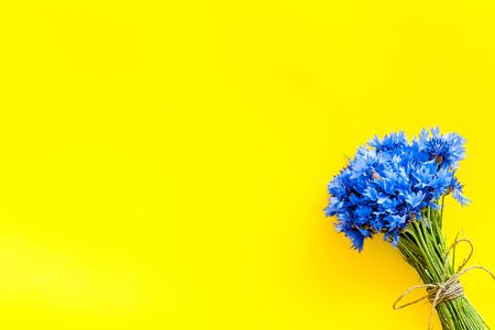 Field flowers. Summer design for blog with bouquet of blue cornflowers on yellow background top view copyspaceの写真素材
