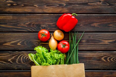 Healthy food with fresh vegetables in paper bag on wooden  top viewの写真素材