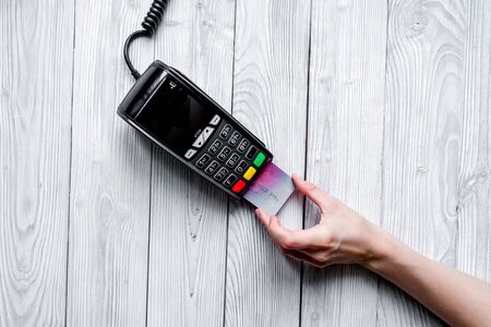 payment card through terminal in store top view on wooden background