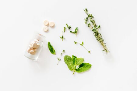 Alternative medicine with medicinal herbs and pills on white background top view.