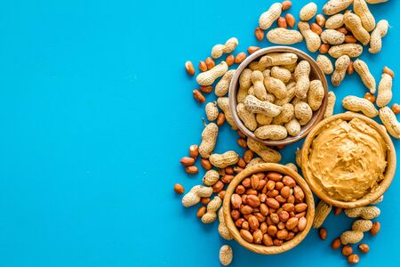 Product for hearty breakfast with peanut butter in bowl near nuts on blue top view mockupの写真素材