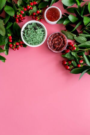 Cosmetics for face with scrub, salt from herbs and berries on pink background top view copyspaceの写真素材