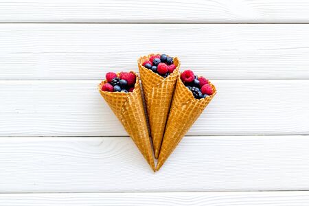 Fresh berries in waffle cones on white wooden background top viewの写真素材