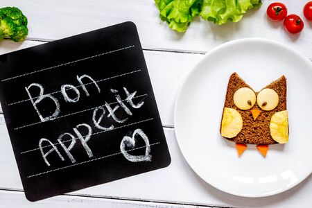 children's breakfast owl shaped sandwich on white plate with vegetables top view at wooden background bon appetitの写真素材