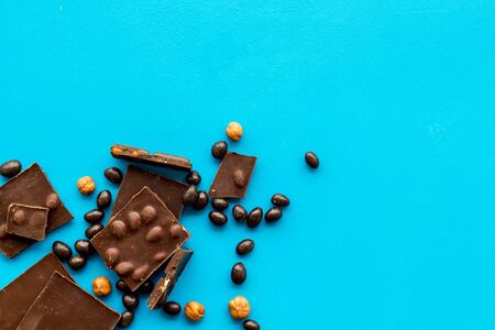 Different variety of chocolate and hazelnut on blue background top view space for text