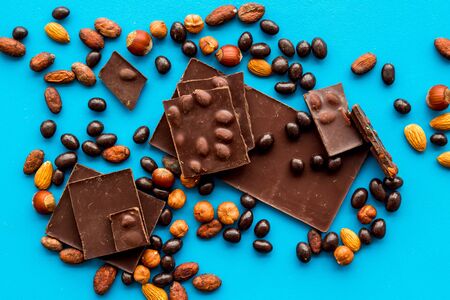Chocolate bars and nuts on blue table background top viewの写真素材