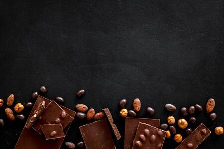 Different variety of chocolate and hazelnut on black background top view space for text