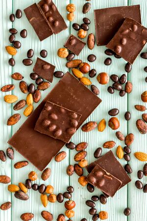 Chocolate bars and nuts on mint green wooden table background top viewの写真素材
