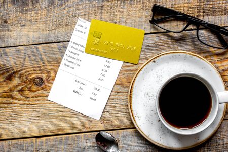 credit card for paying, cup of coffee and check on cafe wooden desk background top viewの写真素材