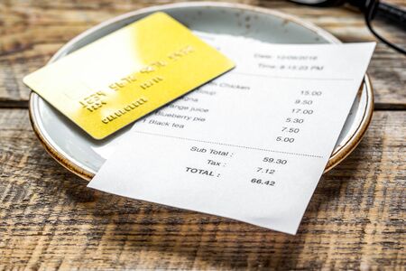 credit card for paying, plate, glasses and check on cafe wooden desk backgroundの写真素材