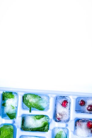 Ice cubes with berries and mint white background top view mock upの写真素材
