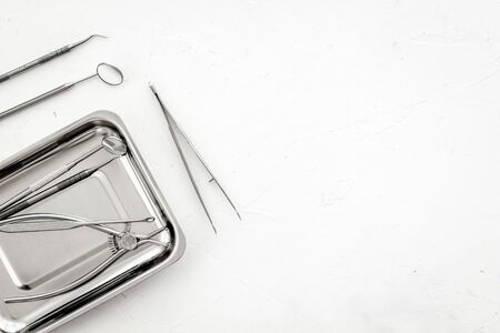 Stomatological tools in tray on dentists desk on white background top-down frame copy space