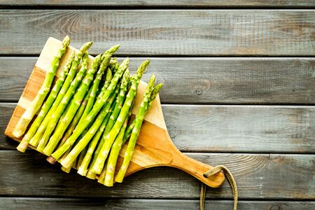 Cooking asparagus. Fresh steams on cutting board on dark wooden background top-down copy spaceの写真素材