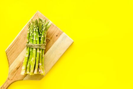 Cooking asparagus. Bunch steams on cutting board on yellow background top-down copy spaceの写真素材