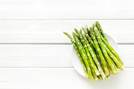 Fresh asparagus on plate on white wooden background top-down copy spaceの写真素材