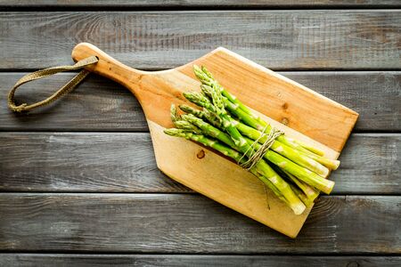 Cooking asparagus. Bunch steams on cutting board on dark wooden background top-down.の写真素材