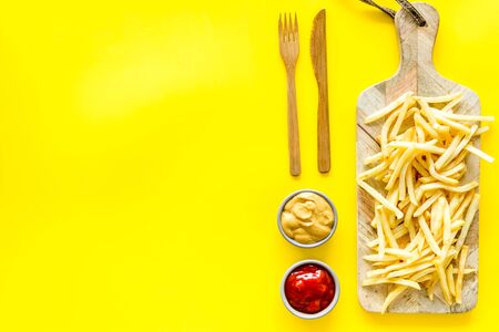 French fries served on cutting board on yellow table top-down.の写真素材