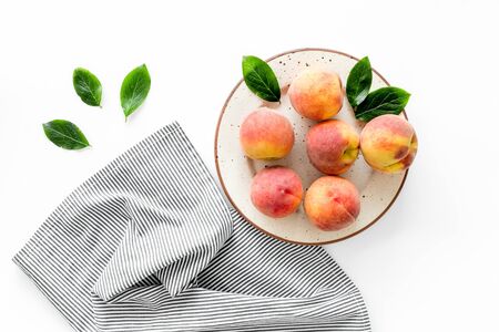 Summer lunch. Red peaches on white background with tablecloth and leaves top-downの写真素材