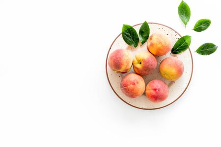 Summer fruits. Ripe red peaches on plate on white table top-down copy spaceの写真素材