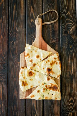 Make focaccia. Traditional italian bread on cutting board on dark wooden table top-down