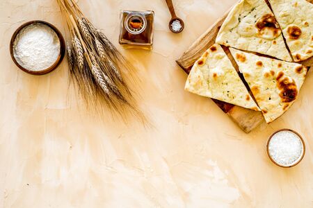 Focaccia ingredients. Wheat ears, flour, oil near bread on beige